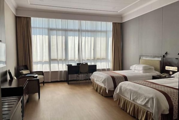Quarto de hotel com duas camas, uma escrivaninha, uma cadeira e um piano.
