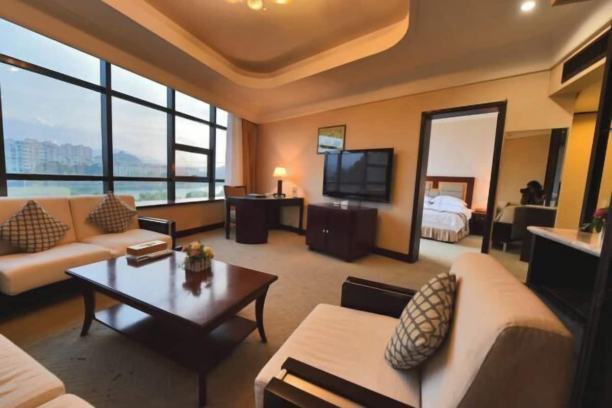 Une chambre d’hôtel avec un canapé, une table basse, une télévision et un lit.