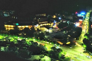 Vista nocturna de un edificio con múltiples ventanas iluminadas y un área de estacionamiento.