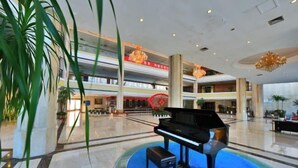 A grand piano in a spacious lobby with multiple floors and a chandelier. - SMQJSZ (Sanmen)