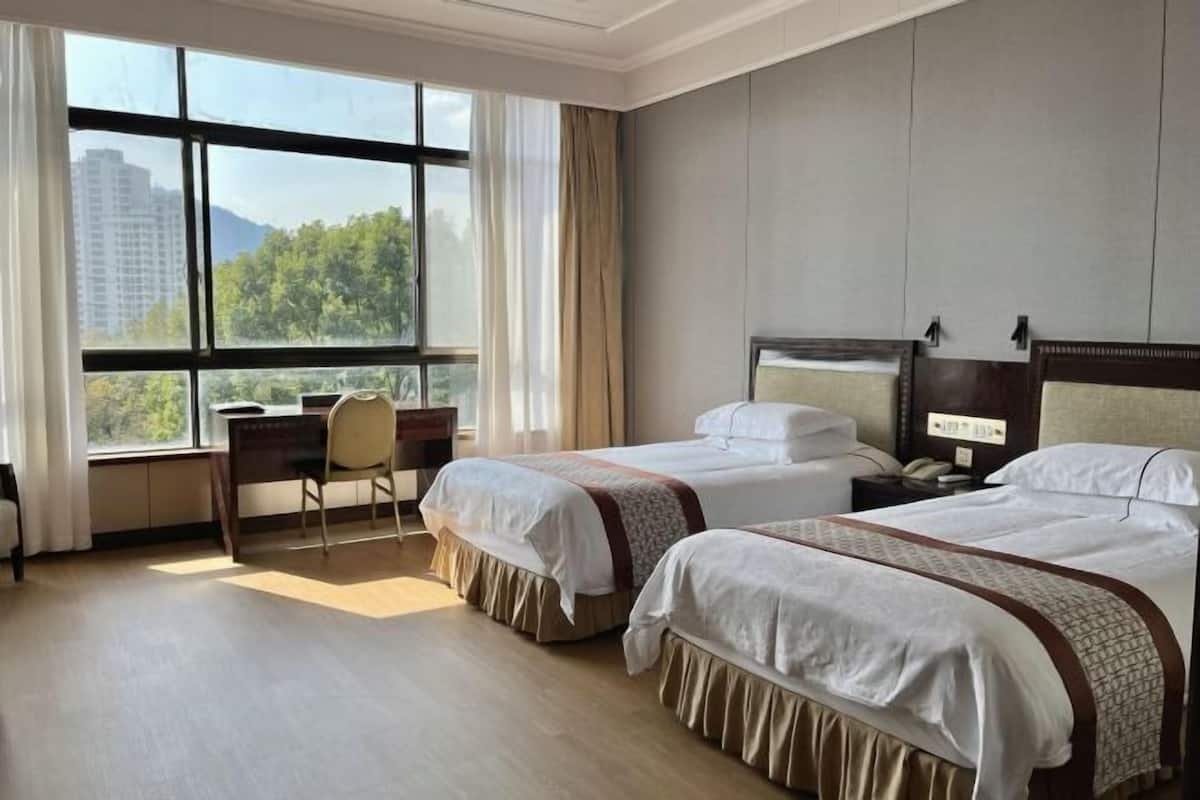 Une chambre d’hôtel avec deux lits, un bureau et une chaise.