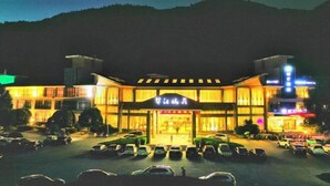 A hotel with a large parking lot and a prominent entrance. - SMQJSZ (Sanmen)