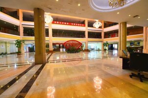 Un vestíbulo amplio con una estructura decorativa roja en el centro, varios niveles y un candelabro moderno.