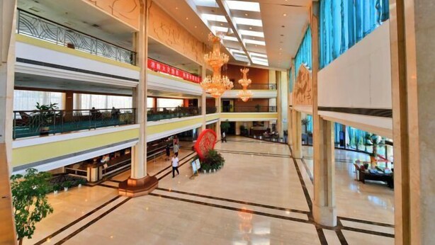 A multi-level atrium with a central open space, glass railings, and decorative lighting fixtures. - SMQJSZ (Sanmen)