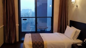 A hotel room with two beds, a view through a large window, and a small table by the window. - Jiacheng Boutique Apartment Hotel (Changsha)