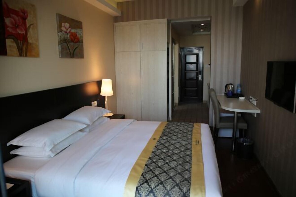 Una habitación de hotel con una cama, un escritorio, una silla, un televisor y una puerta que da a un baño.