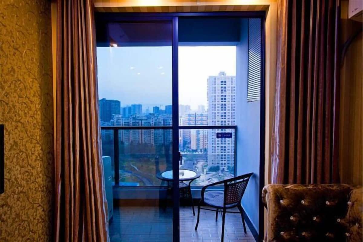 Un balcón con vista a la ciudad, una mesa y dos sillas.