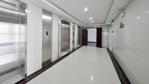 A modern hotel corridor with glass doors, a clean tiled floor, and recessed ceiling lighting. - Jiacheng Boutique Apartment Hotel (Changsha)