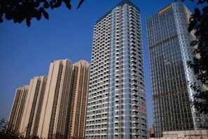 Un edificio de gran altura con un diseño arquitectónico moderno, que presenta una fachada en forma de cuadrícula y una entrada de esquina destacada.