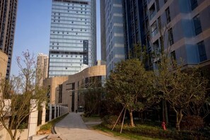 A pathway leading to a modern building with a glass facade, surrounded by trees and a clear sky. - Jiacheng Boutique Apartment Hotel (Changsha)