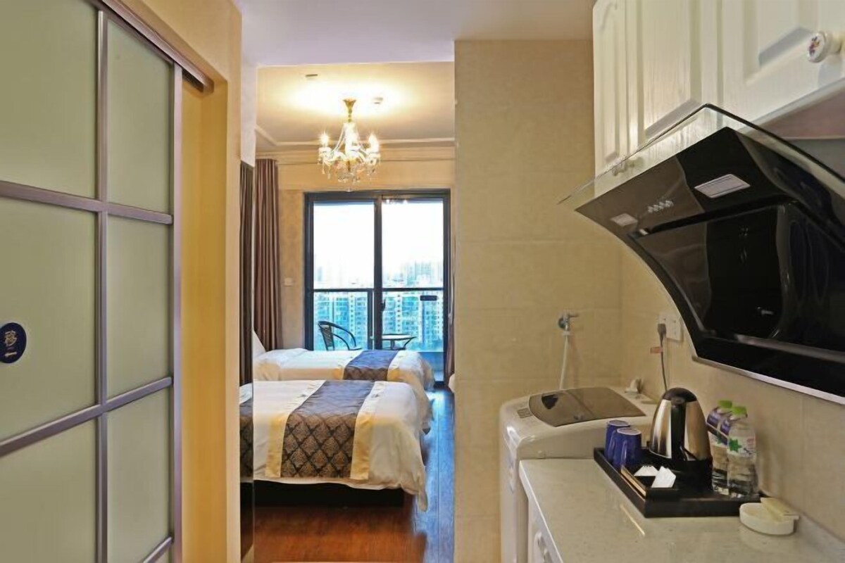 Una habitación de hotel con cama, kitchenette, ventana con vistas y un candelabro.