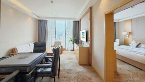 Een hotelkamer met een bed, een bureau met stoel, een televisie en uitzicht op de stad.
