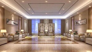 Een ruime hotellobby met een centraal zitgedeelte, diverse bijzettafels en ingelijste kunstwerken aan de wanden.