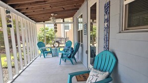 A covered porch with turquoise chairs and a wooden ceiling. - "Salty Dogs: Your Dog-Friendly Haven for Coastal Getaways!" (Oak Island)