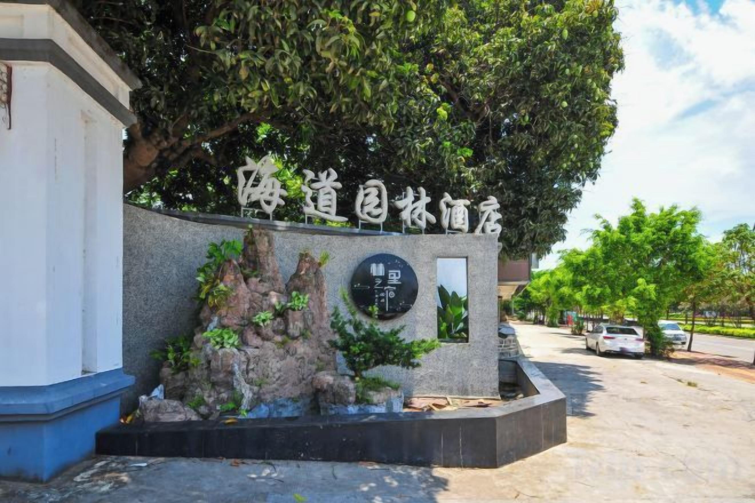 Un letrero con caracteres chinos, una pared de piedra y un árbol.
