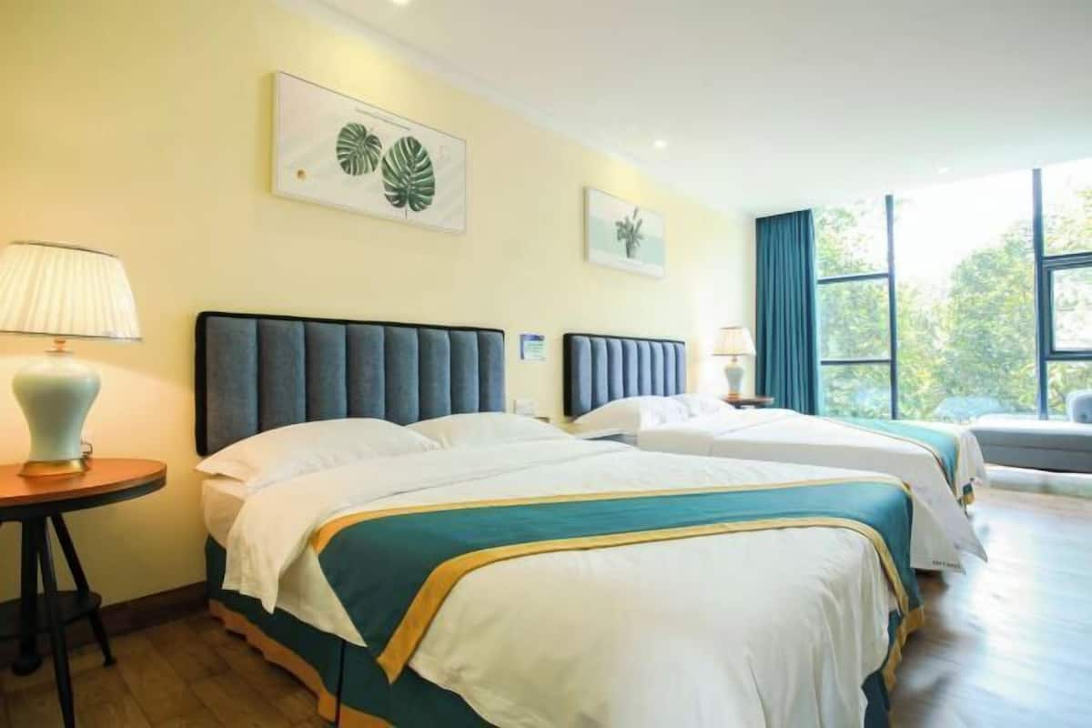 Habitación de hotel con dos camas, una mesita de noche con lámpara y una obra de arte en la pared.