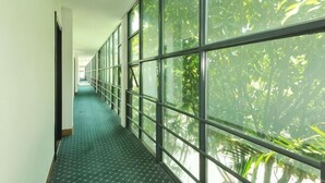 Un pasillo con amplias ventanas, suelo estampado y vistas a árboles.