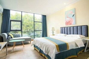 Habitación de hotel con cama, sofá, una mesita y ventana con cortinas.