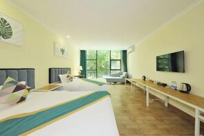 Habitación de hotel con dos camas, un televisor, un escritorio y ventana con vistas a zonas verdes.