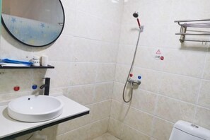 A bathroom with a white sink, a round mirror, a shower with a handheld showerhead, and a toilet. - Yujiacheng Hotel (Fuqing)
