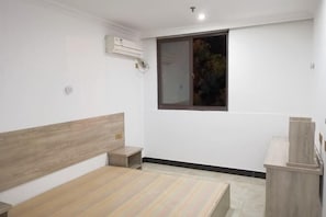 A bedroom with a wooden headboard, a small bedside table, a built-in bench, and a window with a view of trees. - Yujiacheng Hotel (Fuqing)