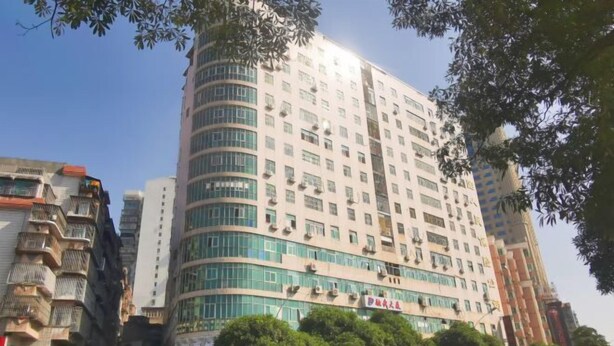Un hotel de varios pisos con fachada curva, ventanas grandes y unidades de aire acondicionado.