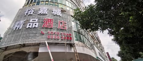 A hotel with a curved facade, large windows, and a signboard with text.