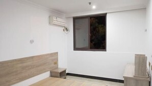 Un dormitorio con cabecera de madera, una mesita de noche pequeña, un armario empotrado y una ventana con vistas a árboles.