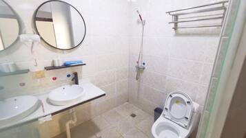 A small bathroom with two sinks, a toilet, a shower, and a mirror.