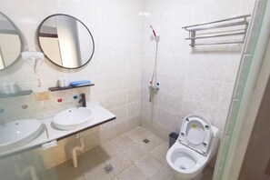 A small bathroom with two sinks, a toilet, a shower, and a mirror. - Yujiacheng Hotel (Fuqing)
