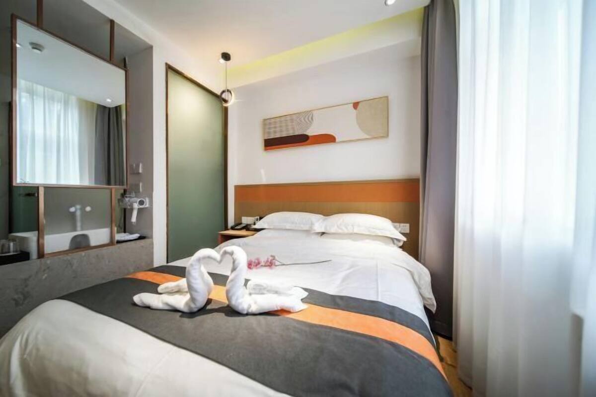 Una habitació d'hotel amb un llit gran, una taula de nit, un mirall i una obra d'art penjada a la paret.