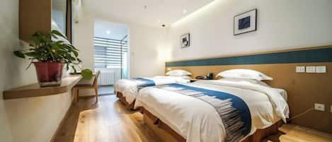 A hotel room with two beds, a potted plant, a wooden floor, and a view of the outside.