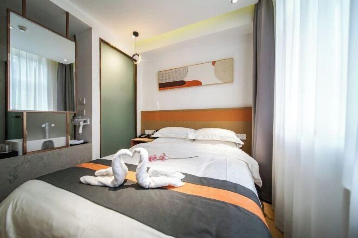 Une chambre d’hôtel avec un lit, un miroir, une table de chevet et une œuvre d’art accrochée au mur.