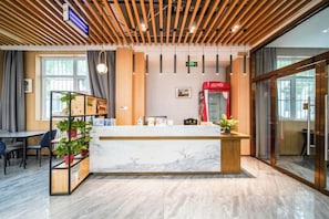 A reception area with a marble counter, wooden ceiling, and a red vending machine. - Xidian Hotel (Xi'an University of Electronic Technology Taibai South Road Subway Station) (Xi'an)