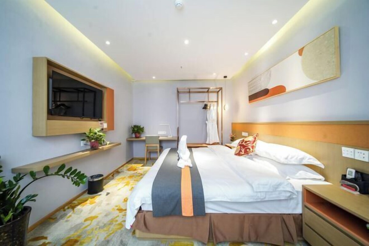 Une chambre d’hôtel avec un lit, une table de chevet, une lampe et un miroir au mur.