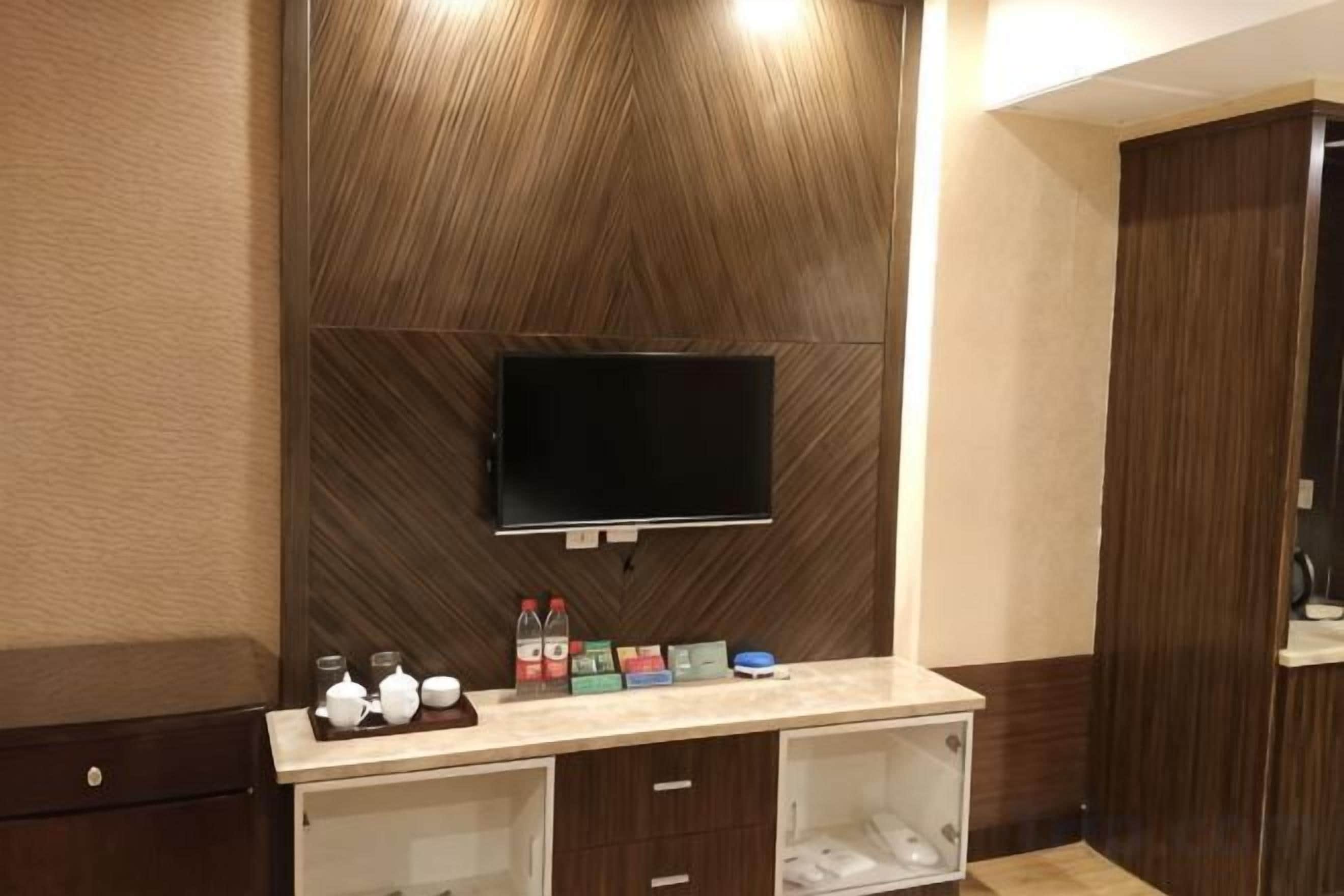 Un baño moderno con un panel de pared de madera, un televisor montado y un mueble de tocador con espejo y espacio de almacenamiento.