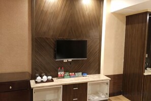 A modern bathroom with a wooden wall panel, a mounted television, and a vanity with a mirror and storage. - Tiandu Hotel (Cixi)