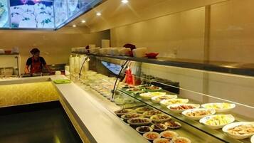 A buffet area with various food options and a staff member attending to it.