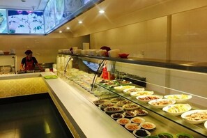A buffet area with various food options and a staff member attending to it. - Tiandu Hotel (Cixi)