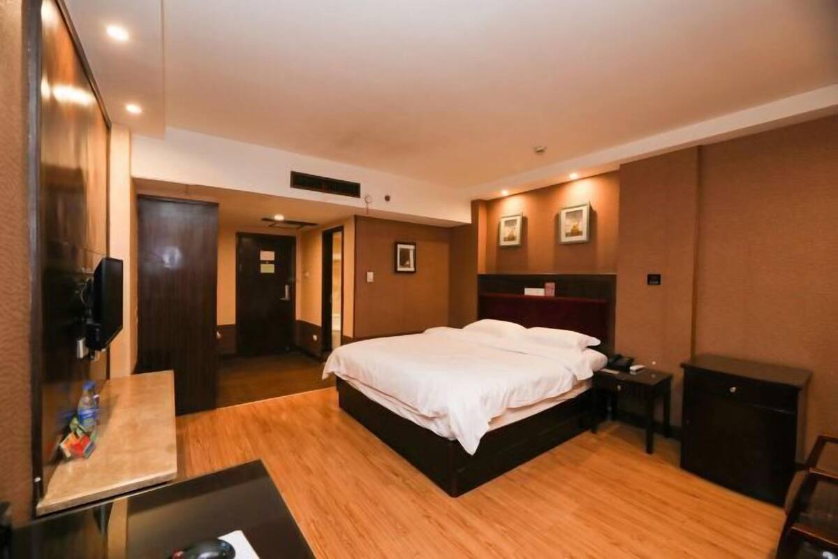 A hotel room with a bed, a desk, a chair, a TV, and a wardrobe.