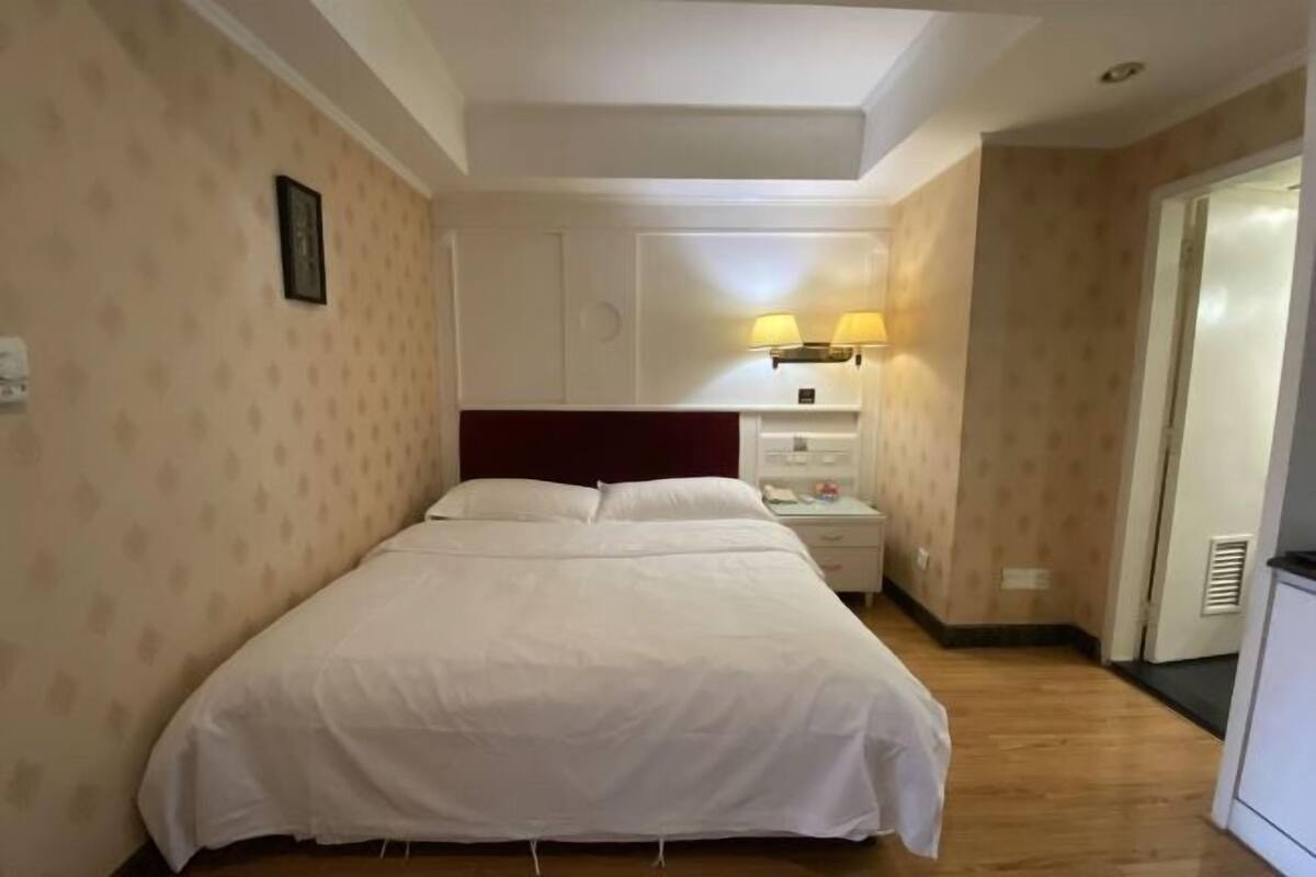 A neatly arranged bedroom with a single bed, a nightstand, a lamp, and a wardrobe.