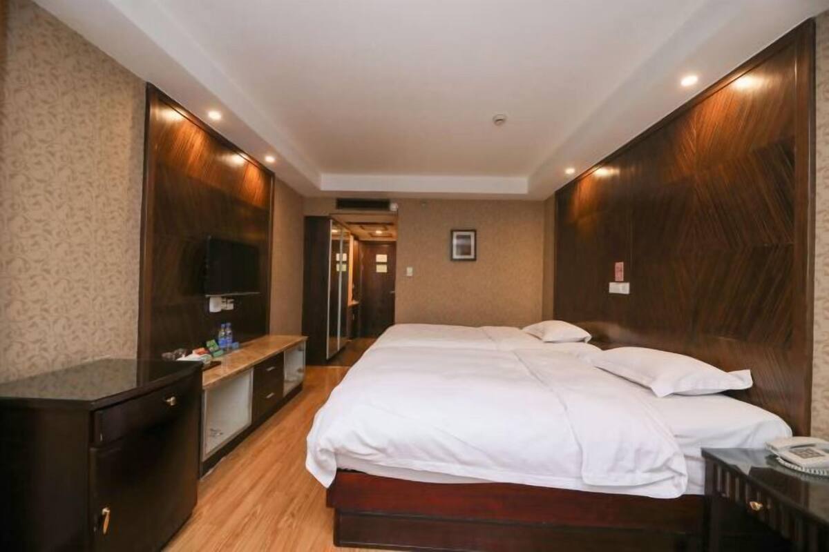 A hotel room with a bed, a TV, a desk, and a wardrobe.