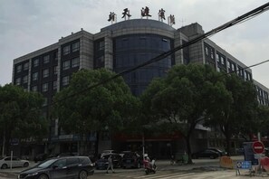 A multi-story building with a curved facade and a sign above the entrance. - Tiandu Hotel (Cixi)