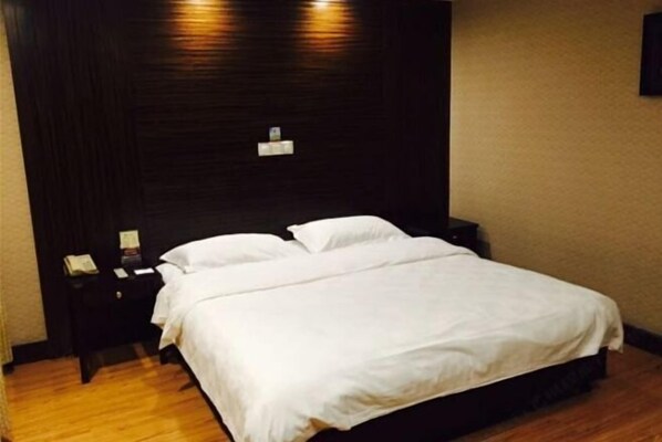 Una habitación de hotel con una cama grande, una mesita de noche y un aplique de pared.