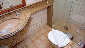 Une salle de bain avec un lavabo sur un plan de travail en granit, des toilettes et une douche à parois de verre.