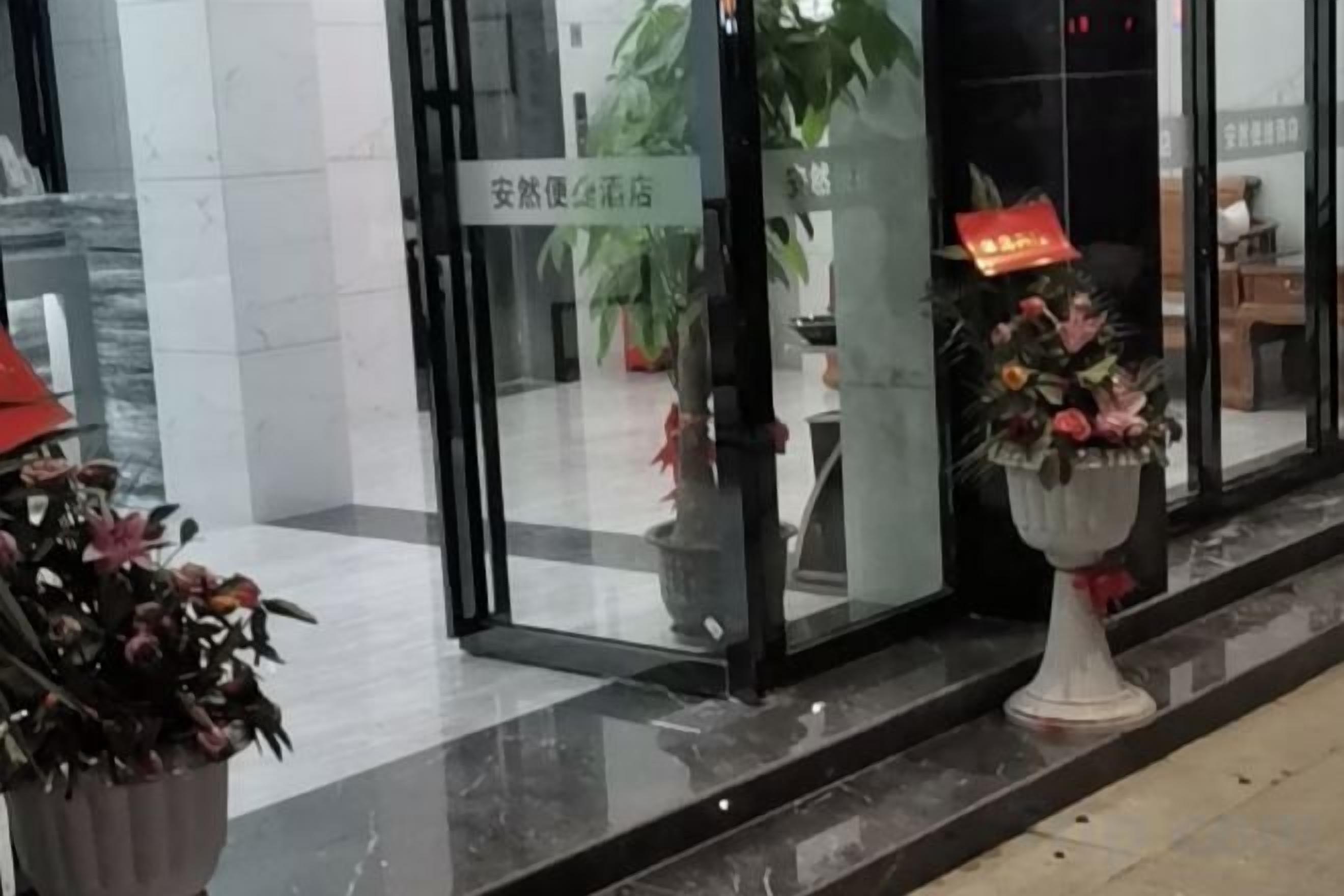 Ein Hotel Eingang mit Schild, Blumentopf und Sitzbereich.