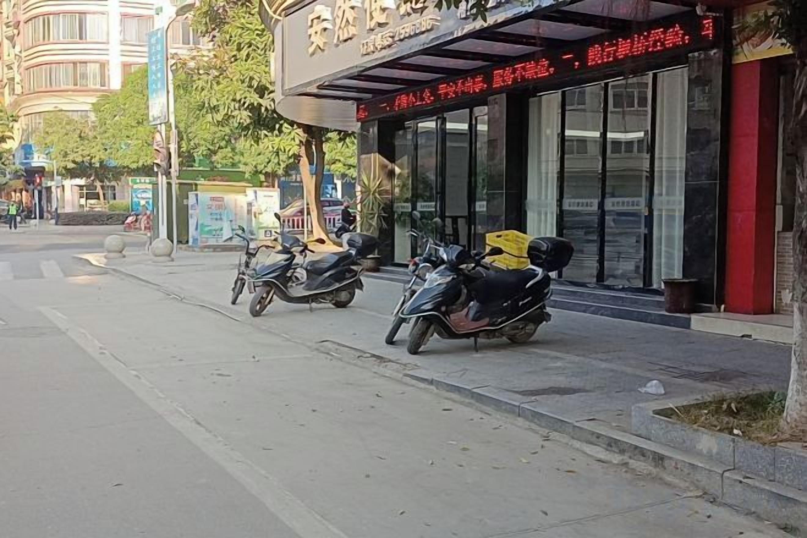 A street with parked scooters and a building with a sign.