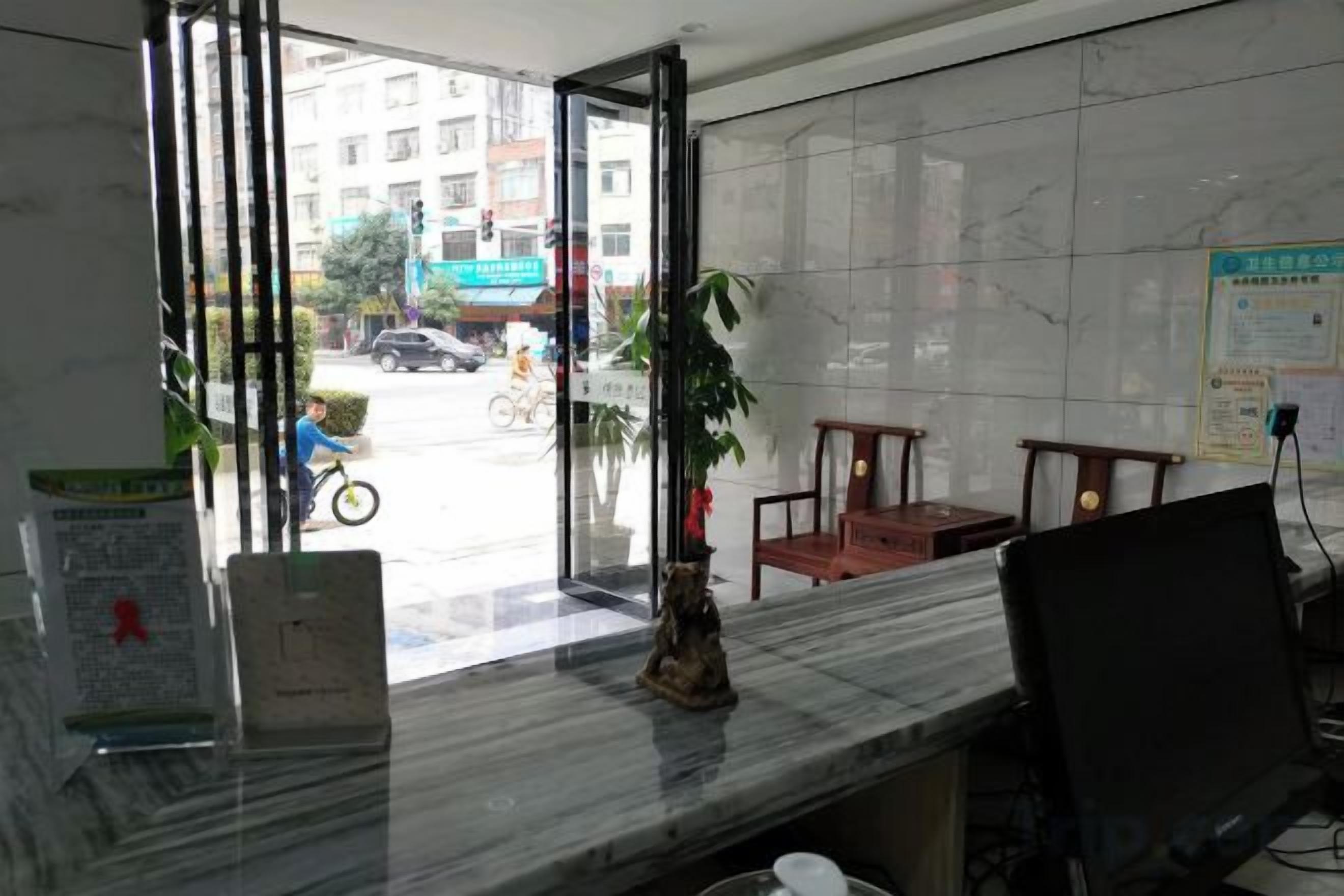 A reception desk with a marble top, a potted plant, and a chair.
