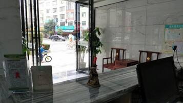 A reception desk with a marble top, a potted plant, and a chair.