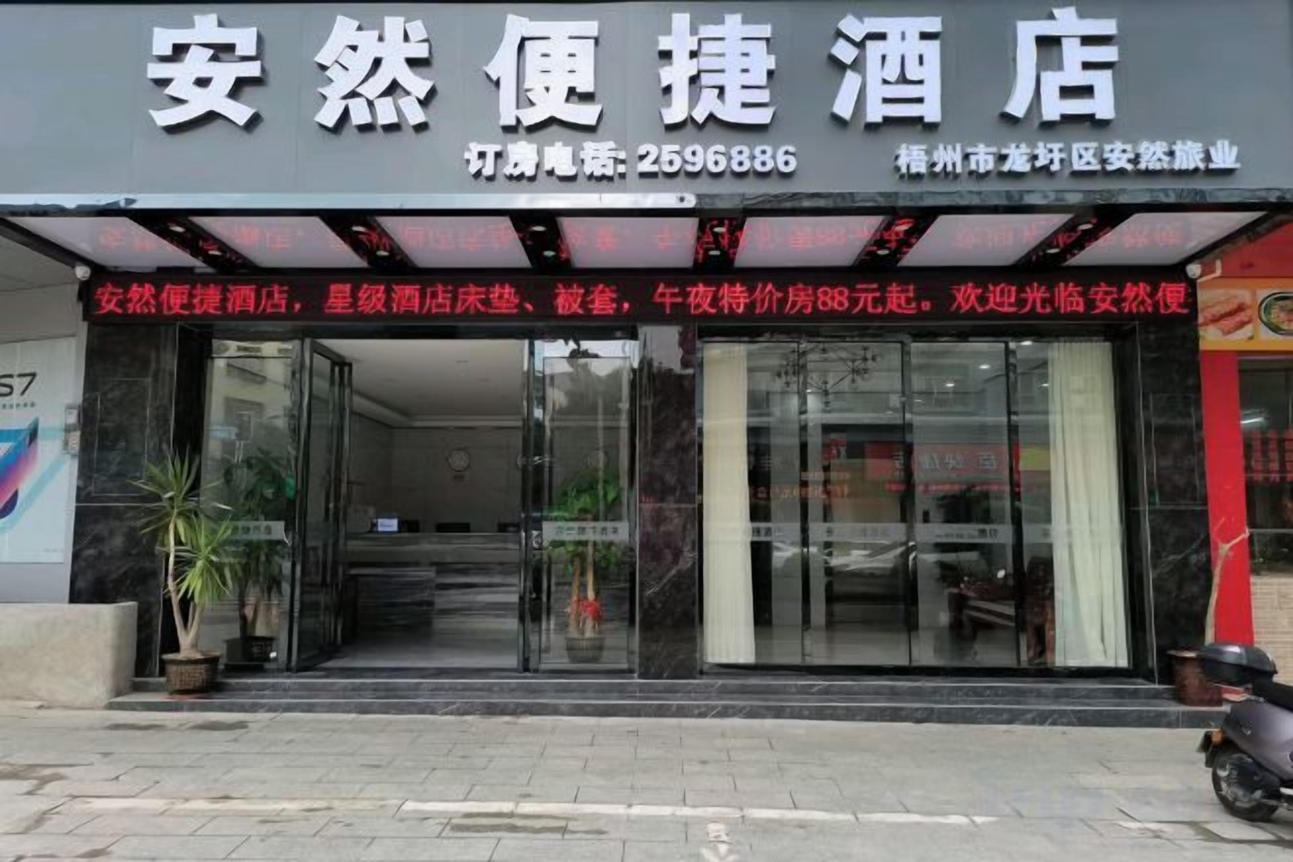 A hotel entrance with a glass facade, a reception desk, and a staircase leading inside.